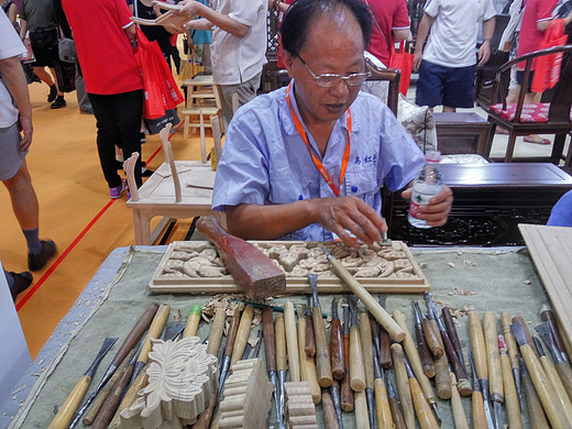 上海家博会在北京举办了三天，展厅里的老人在认真雕刻，他雕刻的木雕就会被买走。